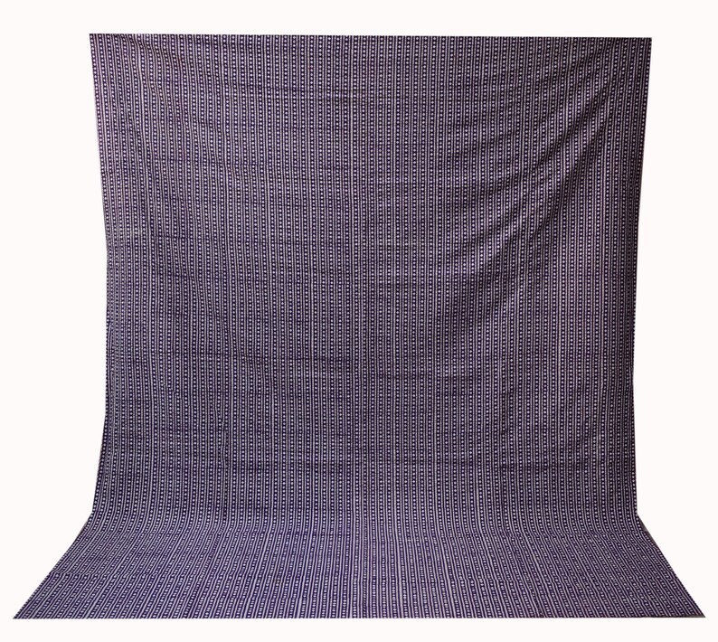 May include: A large, dark purple fabric backdrop with a repeating pattern of small white squares.