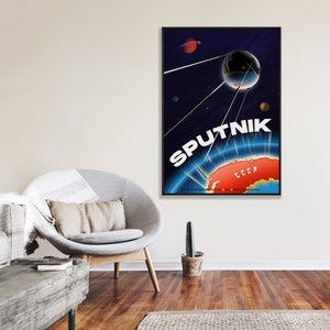 May include: A vintage-style poster with a blue and black background depicting a satellite orbiting Earth. The satellite is connected to Earth by a series of lines. The text "SPUTNIK" is written in white letters on the poster. The text "CCCP" is written in red letters on the poster. The poster is framed in black.