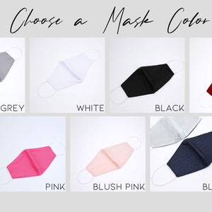 May include: A selection of face masks in various colors, including grey, white, black, red, pink, blush pink, and blue. The masks are all made of fabric and have elastic ear loops.
