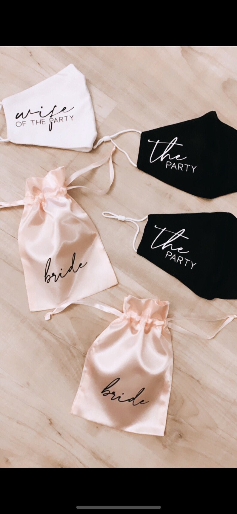 May include: Two black face masks with white text that says "the party" and two pink satin bags with black text that says "bride".