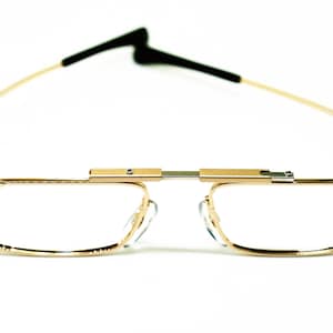 May include: Gold-tone metal eyeglasses with a flexible bridge and clear lenses.