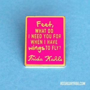 May include: A pink enamel pin with gold trim featuring a quote by Frida Kahlo: "Feet, what do I need you for when I have wings to fly?"