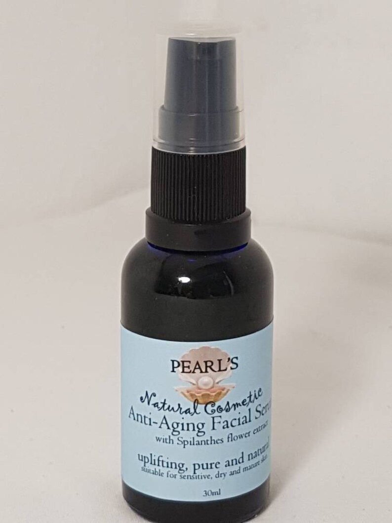 May include: A dark blue glass bottle of Pearl's Natural Cosmetic Anti-Aging Facial Serum. The label is light blue with white text and a seashell graphic. The bottle has a black pump and a clear plastic cap. The bottle contains 30ml of serum.