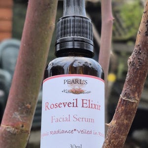 May include: A brown glass bottle of Roseveil Elixir facial serum with a black dropper. The label reads "Pearl's Natural Cosmetic" and "Roseveil Elixir Facial Serum". The bottle contains 30ml of product.