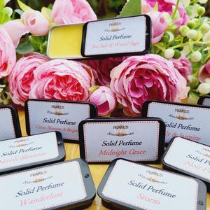 Puede incluir: Una colección de diez pequeñas latas redondas negras con etiquetas blancas. Cada lata contiene perfume sólido y está etiquetada con el nombre del aroma. Los aromas incluyen Rouge 540, Sal Marina & Madera de Sándalo, Flor de Cítricos & Bergamota, Flor de Azahar, Anhelo de Viaje, Gracia de Medianoche, Lirio & Jazmín, Tormenta, Mujer Negra y Avellana.