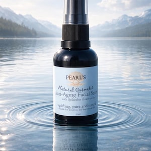 May include: A black bottle of Pearl's Natural Cosmetic Anti-Aging Facial Serum with a spray nozzle. The label includes the text "uplifting, pure and natural". The bottle is reflected in the water, with mountains in the background.