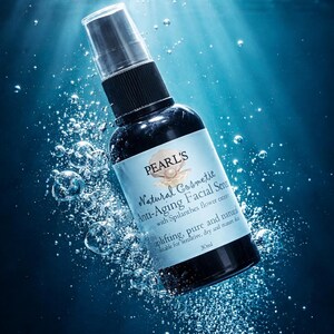 May include: A black bottle of Pearl's Natural Cosmetic Anti-Aging Facial Serum with a clear spray top. The label includes the text "uplifting, pure and natural" and "30ml". The background is a blue aquatic scene with bubbles.