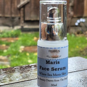 May include: A clear glass bottle of Maris Face Serum with a silver pump top. The label is white and light blue, with the text "PEARL'S Natural Care" and "Where Sea Meets Skin". The bottle contains 30ml of product.