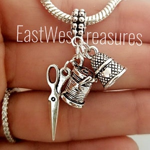 May include: Silver charm bracelet with a silver thimble, spool of thread, and scissors charm. The charms are attached to a silver chain.