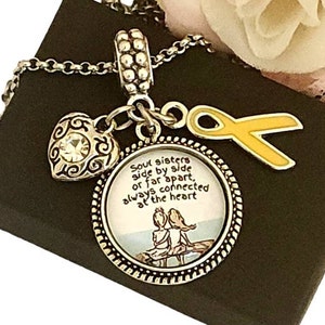 May include: Silver charm bracelet with a heart charm, a charm with the text "Soul sisters side by side or far apart, always connected at the heart", and a yellow ribbon charm.