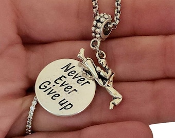 May include: Silver necklace with a round charm that says "Never Ever Give Up" and a charm of a person doing a martial arts kick.