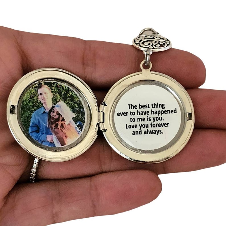 May include: Silver locket necklace with a heart-shaped bail. The locket opens to reveal a photo of a couple and a message inside that reads: "The best thing ever to have happened to me is you. Love you forever and always."