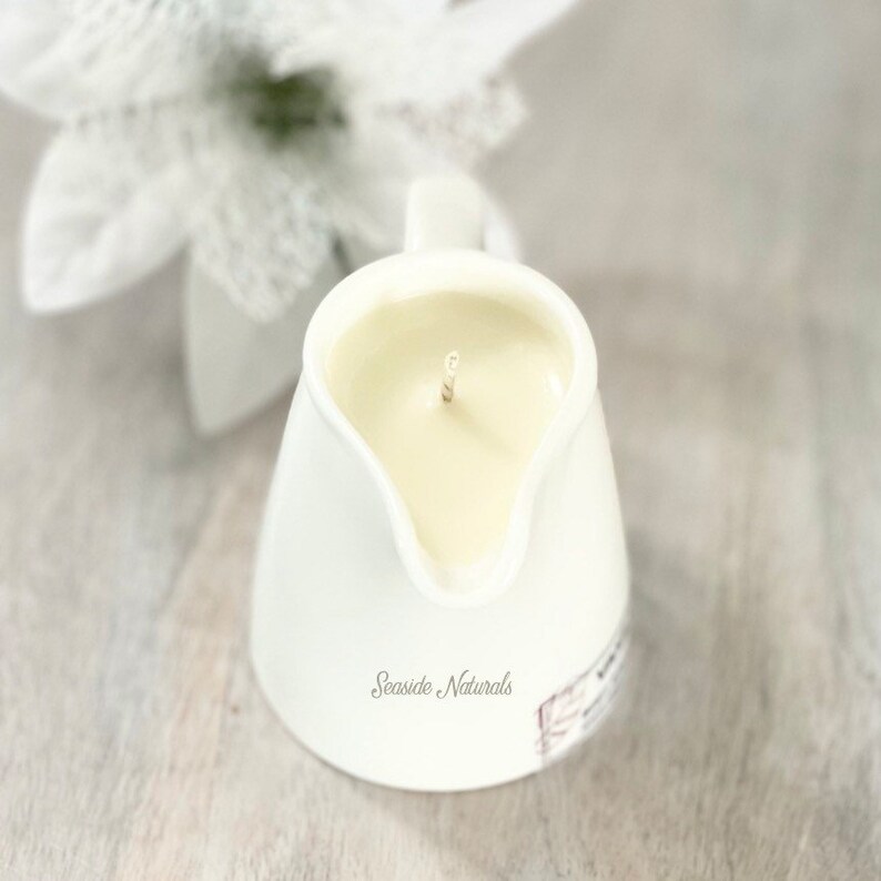 May include: White ceramic pitcher candle with a single wick and the text "Seaside Naturals" on the bottom.