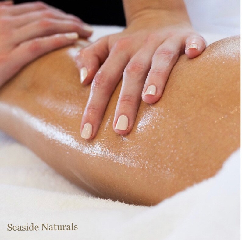 May include: Close-up of a person's leg receiving a massage with oil. The skin is smooth and shiny, and the hands are gently applying pressure.