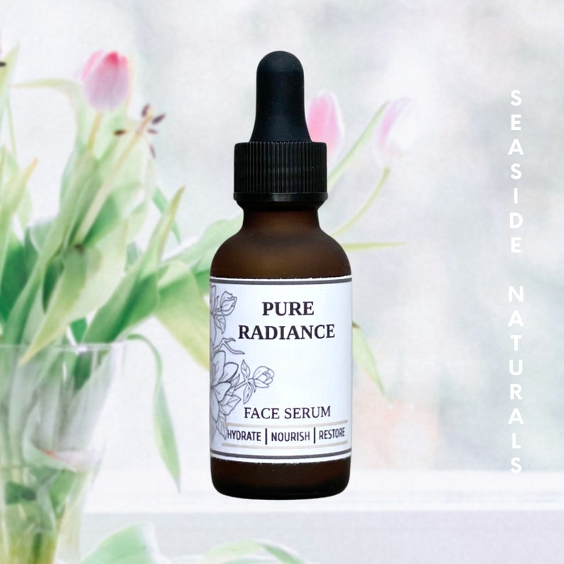 May include: A brown glass bottle with a dropper top, labeled "Pure Radiance Face Serum" with the text "Hydrate | Nourish | Restore" underneath. The bottle is sitting on a white surface with a blurred background of pink flowers.