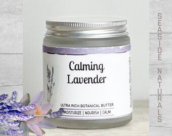 Puede incluir: Un tarro de vidrio con tapa plateada lleno de crema blanca. La etiqueta dice "Calming Lavender Ultra Rich Botanical Butter Moisturize | Nourish | Calm".