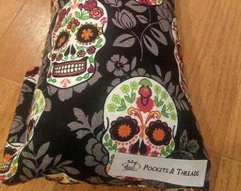 Puede incluir: Almohada de tela negra con un patrón repetido de calaveras de azúcar coloridas y diseños florales. La almohada tiene una etiqueta blanca con el texto "Pockets & Threads".