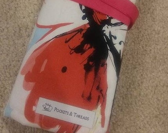 Puede incluir: Un estuche enrollable de tela blanca con cierre de cinta rosa. El estuche presenta un diseño floral abstracto colorido con acentos rojos, negros y azules. El estuche tiene una etiqueta que dice "Pockets & Threads".