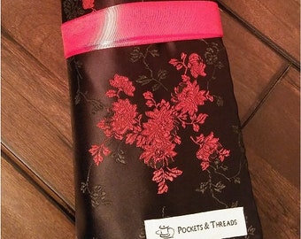 Puede incluir: Una envoltura de corbata de tela negra y roja con un patrón floral y el texto "Pockets & Threads".