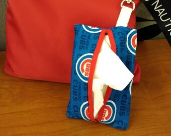 Puede incluir: Bolso bandolera rojo con una etiqueta de metal plateado que dice "NAUTICA" y un porta pañuelos azul y blanco con el logotipo de los Chicago Cubs.