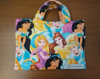 Puede incluir: Bolso tote rectangular de tela con un estampado de princesas animadas. El bolso tiene un asa y muestra princesas en varias poses y atuendos. La etiqueta del bolso dice "Pockets & Threads".