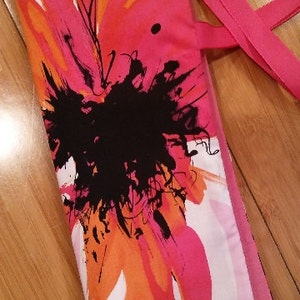 May include: A pink and orange floral print fabric tote bag with a black and white abstract design. The bag has a pink strap and a white label with the text "Pockets & Threads".