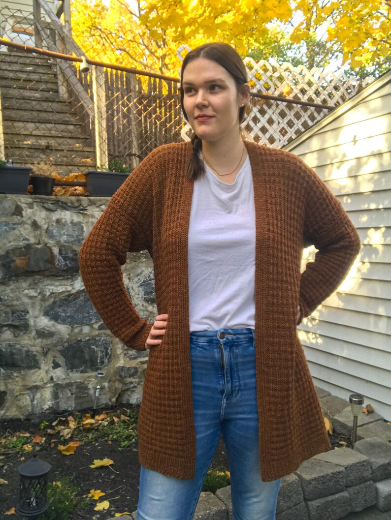 May include: A brown waffle knit cardigan with long sleeves and a relaxed fit. The cardigan is open in the front and has a slightly longer length.