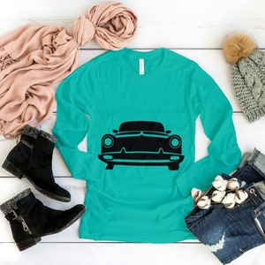 May include: A turquoise long-sleeved shirt with a black silhouette of a classic car on the front.