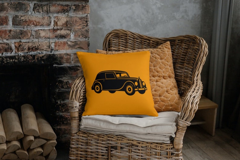 May include: A yellow throw pillow with a black silhouette of a vintage car. The pillow is sitting on a wicker chair.