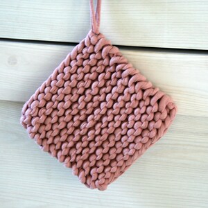 May include: A pink knitted pot holder with a loop for hanging.