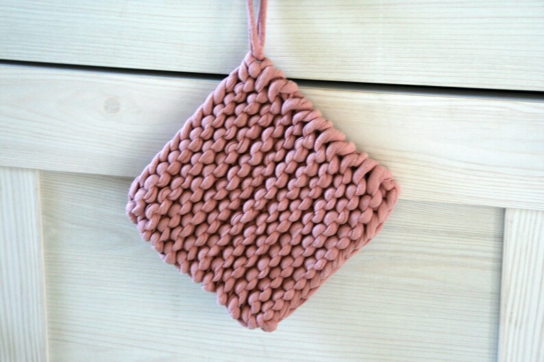 May include: A pink knitted pot holder with a loop for hanging.