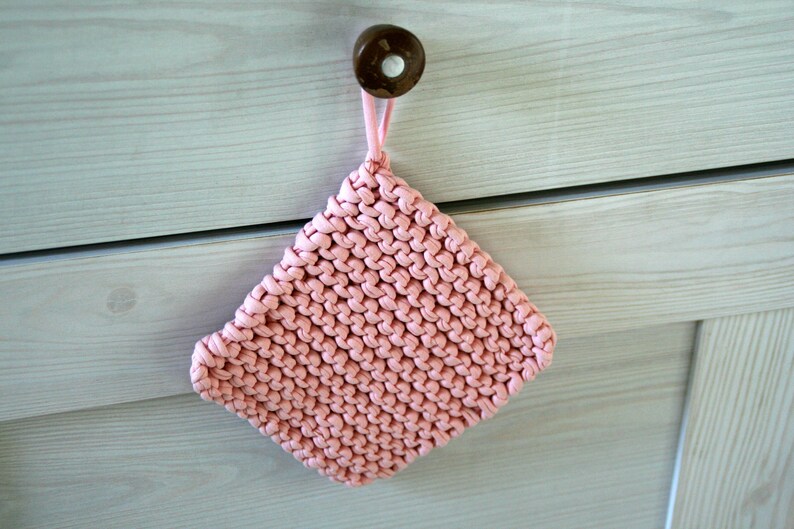 Op de afbeelding: Een roze gebreide ovenwant met een lus om op te hangen.