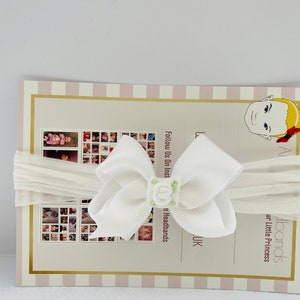 Puede incluir: Diadema blanca con un gran lazo blanco y una pequeña flor verde. La diadema está hecha de un material suave y elástico, perfecta para bebés y niños pequeños.  Síguenos en Instagram @headbands_uk