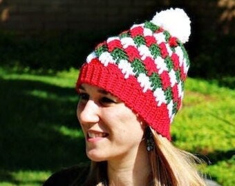 May include: A red, white, and green crocheted beanie with a white pom pom on top. The beanie has a checkered pattern.