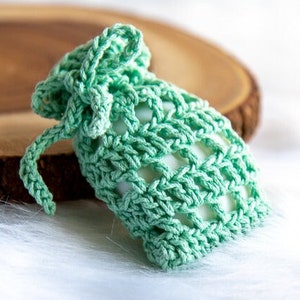 May include: A crocheted green soap sack with a drawstring closure. The sack is made with a simple stitch pattern and is perfect for storing and lathering soap.