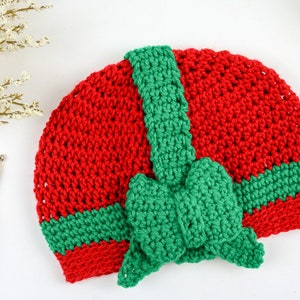 May include: A red and green crocheted hat with a large green bow. The hat is made with a single crochet stitch and has a striped pattern.