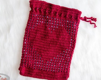 May include: A red crocheted drawstring bag with a lacy pattern. The bag is lying flat on a white surface.