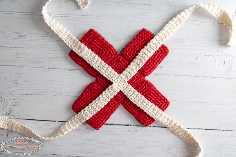 May include: Red and white crocheted pot holders in the shape of an X, with white crocheted ribbon tied around them.