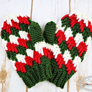 May include: A pair of crocheted mittens in green, white and red. The mittens are made with a textured stitch and have a striped pattern.