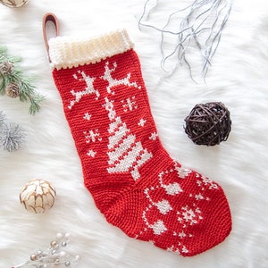 May include: Red and white knitted Christmas stocking with a white crocheted cuff. The stocking features a white tree and reindeer design.