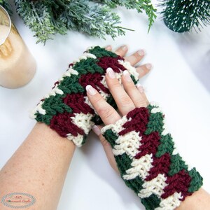 May include: A pair of fingerless gloves with a green, white and burgundy striped pattern. The gloves are crocheted and have a textured look.