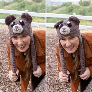 May include: A brown crocheted bear hat with long ear flaps. The hat has black eyes, a white nose, and a brown snout. The hat is being worn by a person with brown hair and a brown leather jacket.