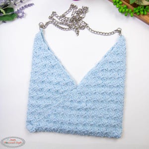 May include: A light blue crocheted bag with a silver chain strap. The bag has a V-shaped opening and a textured surface.