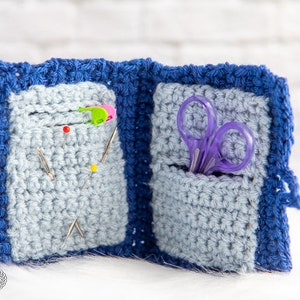 Pu&ograve; includere: Un porta aghi e forbici in crochet blu con due tasche. Una tasca contiene spilli da cucito e l'altra contiene un paio di forbici viola.