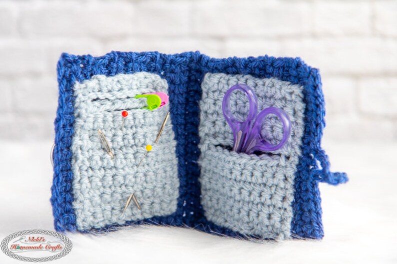 Pu&ograve; includere: Un porta aghi e forbici in crochet blu con due tasche. Una tasca contiene spilli da cucito e l'altra contiene un paio di forbici viola.