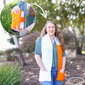 May include: A handmade crochet scarf with a white and orange color block design. The scarf features two pockets and a button closure. The scarf is worn by a person in a green shirt.