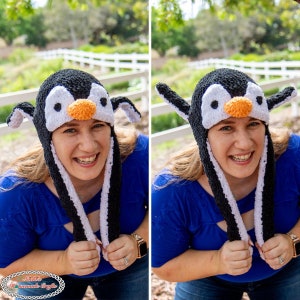 May include: A woman wearing a black and white crocheted penguin hat with orange beak and white eyes. The hat has long ear flaps. She is smiling and holding the ear flaps in her hands.