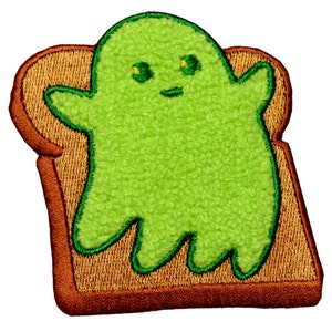 May include: Green ghost-shaped embroidered patch on a brown toast-shaped background.