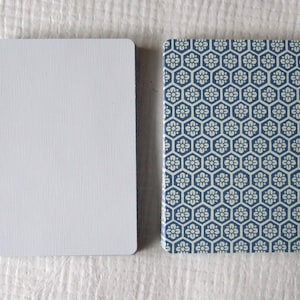May include: Two rectangular cards. One is plain white with a textured surface. The other has a blue and white floral hexagonal pattern. The cards are likely for a game or a decorative purpose.