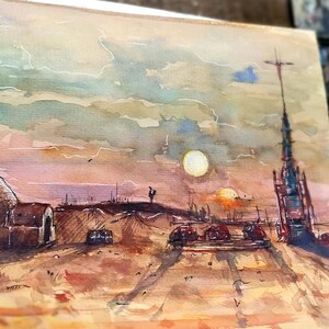 Op de afbeelding: Waterverfschilderij van een woestijnlandschap met een koepelvormige structuur, een hoge toren en ondergaande zonnen. Het kunstwerk gebruikt warme tinten bruin, oranje en geel, met een bewolkte lucht. De schildering is op papier, met een palet en verf op de achtergrond.